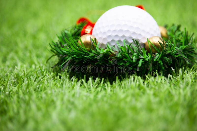 Golf ball with Christmas ornament on green grass , idea for golfer Christmas holiday decoration. Golf ball with Christmas ornament on green grass , idea for golfer Christmas holiday decoration