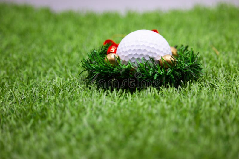 Golf ball with Christmas ornament on green grass , idea for golfer Christmas holiday decoration. Golf ball with Christmas ornament on green grass , idea for golfer Christmas holiday decoration