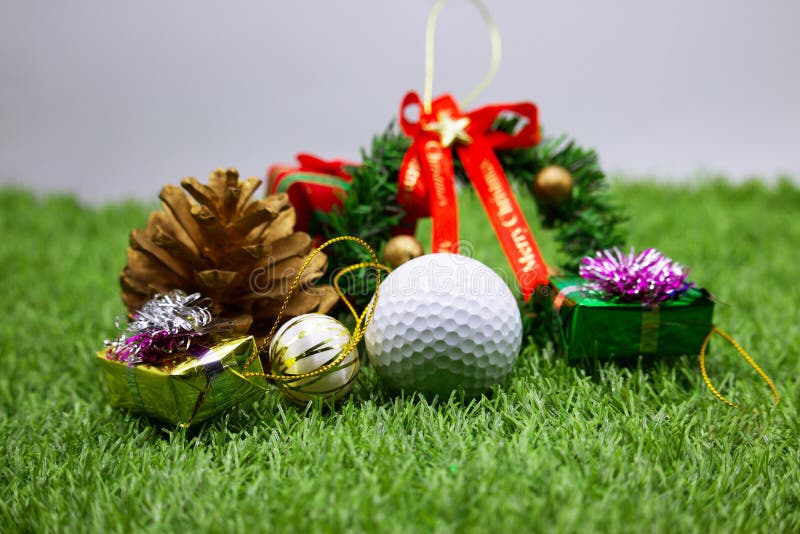 Golf ball with Christmas ornament on green grass , idea for golfer Christmas holiday decoration. Golf ball with Christmas ornament on green grass , idea for golfer Christmas holiday decoration