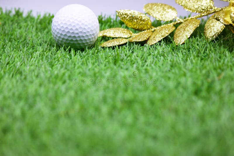 Golf ball with Christmas ornament on green grass , idea for golfer Christmas holiday decoration. Golf ball with Christmas ornament on green grass , idea for golfer Christmas holiday decoration