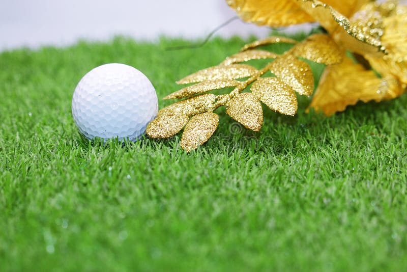 Golf ball with Christmas ornament on green grass , idea for golfer Christmas holiday decoration. Golf ball with Christmas ornament on green grass , idea for golfer Christmas holiday decoration