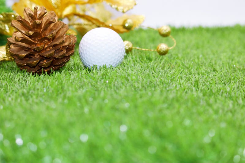 Golf ball with Christmas ornament on green grass , idea for golfer Christmas holiday decoration. Golf ball with Christmas ornament on green grass , idea for golfer Christmas holiday decoration