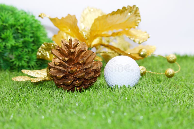 Golf ball with Christmas ornament on green grass , idea for golfer Christmas holiday decoration. Golf ball with Christmas ornament on green grass , idea for golfer Christmas holiday decoration