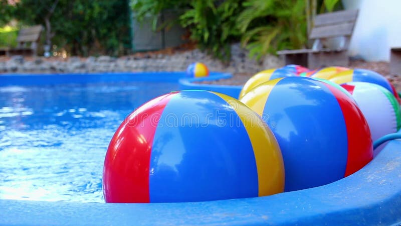 Pelotas de playa coloridas que flotan en piscina