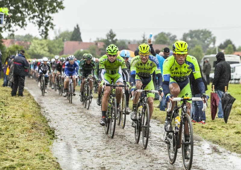 Ennevelin, France - July 09,2014: The cylists Nicolas Roche (Saxo Thinkoff Team) and Maciej Bodnar (Cannondale) following Alberto Contador (Saxo Thinkoff Team) inside the peloton riding on a cobbled road during the stage 5 of Le Tour de France 2014. Ennevelin, France - July 09,2014: The cylists Nicolas Roche (Saxo Thinkoff Team) and Maciej Bodnar (Cannondale) following Alberto Contador (Saxo Thinkoff Team) inside the peloton riding on a cobbled road during the stage 5 of Le Tour de France 2014.