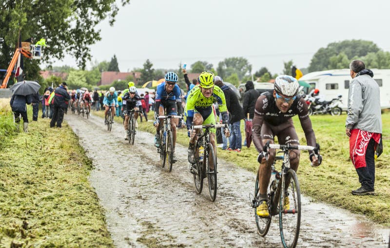 Ennevelin, France - July 09,2014: The peloton riding on a cobbled road during the stage 5 of Le Tour de France 2014. The cyclists Michael Rogers (Saxo-Thinkoff Team) and Andrew Talanski (Garmin Sharp Team) follow Jean Cristophe Peraud (AG2R La Monadiale Team). Ennevelin, France - July 09,2014: The peloton riding on a cobbled road during the stage 5 of Le Tour de France 2014. The cyclists Michael Rogers (Saxo-Thinkoff Team) and Andrew Talanski (Garmin Sharp Team) follow Jean Cristophe Peraud (AG2R La Monadiale Team).