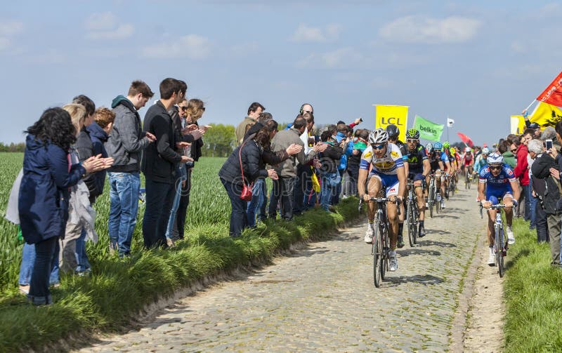 Carrefour de l'Arbre,France-April 13,2014: The peloton riding on the famous cobblestone sector Carrefour de l'Arbre in Camphin-en-Pévèle town during the 2014 edition of Paris-Roubaix cycling race. Carrefour de l'Arbre,France-April 13,2014: The peloton riding on the famous cobblestone sector Carrefour de l'Arbre in Camphin-en-Pévèle town during the 2014 edition of Paris-Roubaix cycling race.