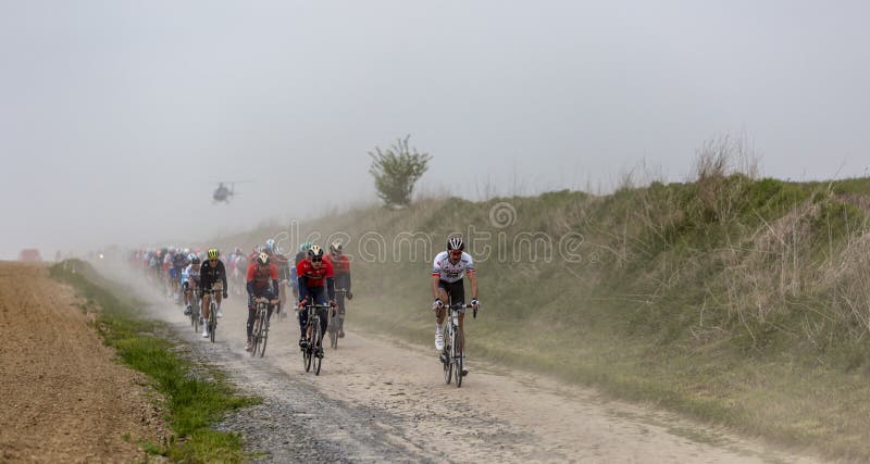 Viesly, France - April 14, 2019: The peloton riding on the dusty cobblestone road from Briastre to Viesly during Paris Roubaix 2019. Viesly, France - April 14, 2019: The peloton riding on the dusty cobblestone road from Briastre to Viesly during Paris Roubaix 2019