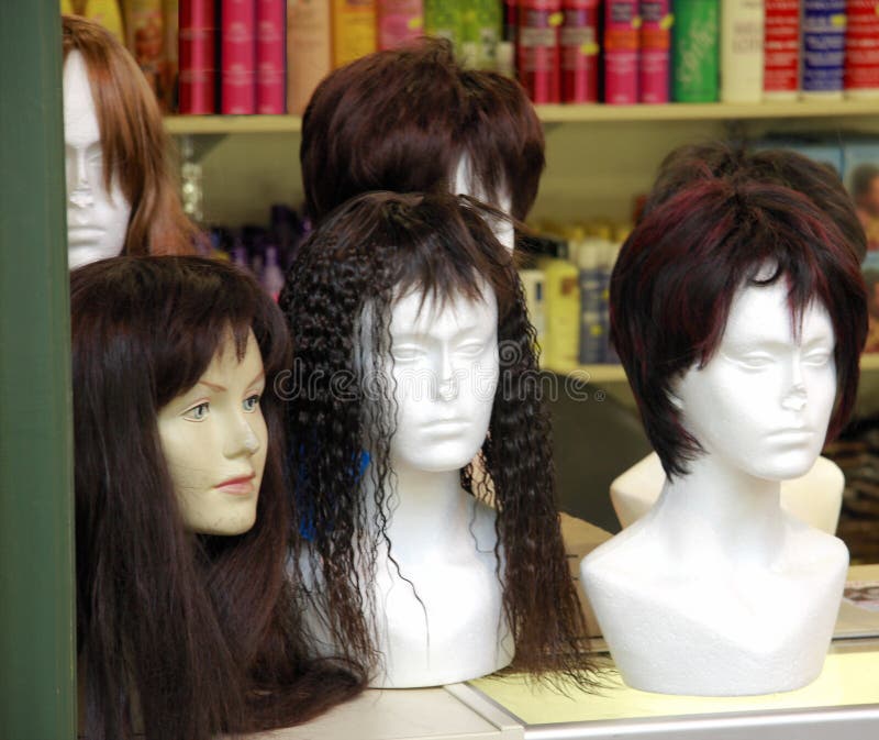 A number of damaged mannequin heads displaying wigs on a shop display counter. A number of damaged mannequin heads displaying wigs on a shop display counter