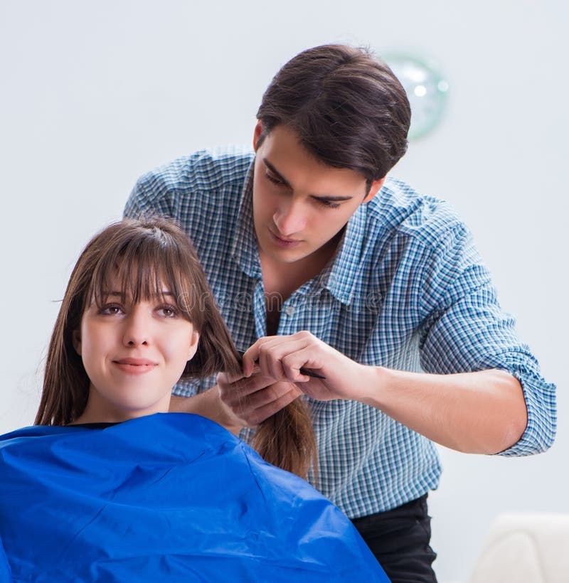 Peluquero de sexo masculino del hombre que hace el corte de pelo para la mujer foto de archivo libre de regalías Peluquero de sexo masculino del hombre que hace el corte de pelo para la mujer foto de archivo libre de regalías