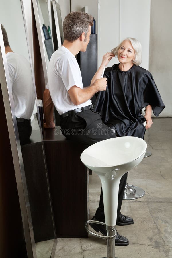 Peluquero que escucha el cliente femenino imagenes de archivo Peluquero que escucha el cliente femenino imagenes de archivo