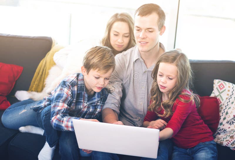 Película de observación de la familia positiva joven en el ordenador portátil junto en casa imagen de archivo libre de regalías Película de observación de la familia positiva joven en el ordenador portátil junto en casa imagen de archivo libre de regalías