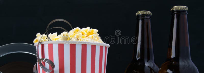 Película en palomitas, en un fondo negro, con dos botellas de cerveza foto de archivo libre de regalías Película en palomitas, en un fondo negro, con dos botellas de cerveza foto de archivo libre de regalías