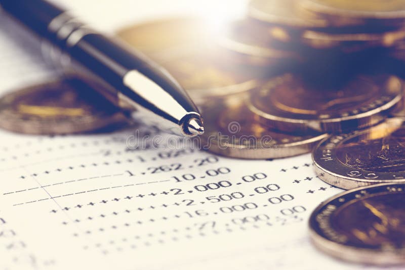 Close up black metal pen and stack of coins on account passbook