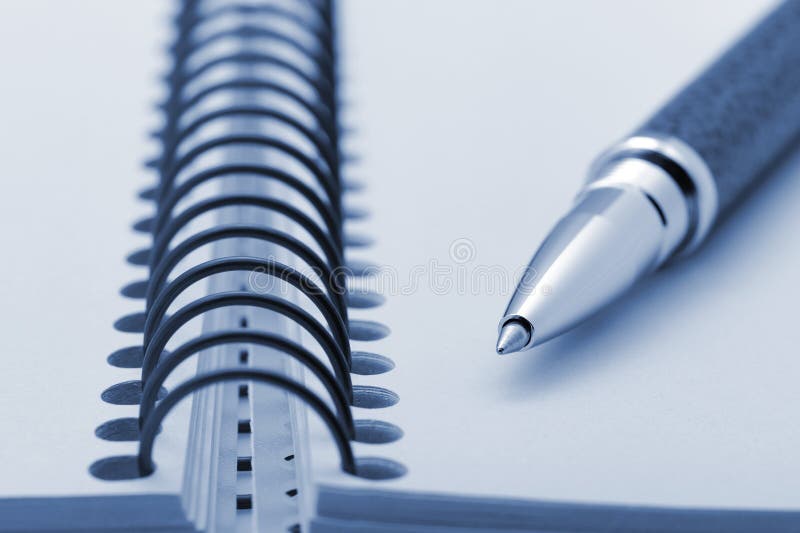 Pen and a notebook on a spiral with a yellow paper