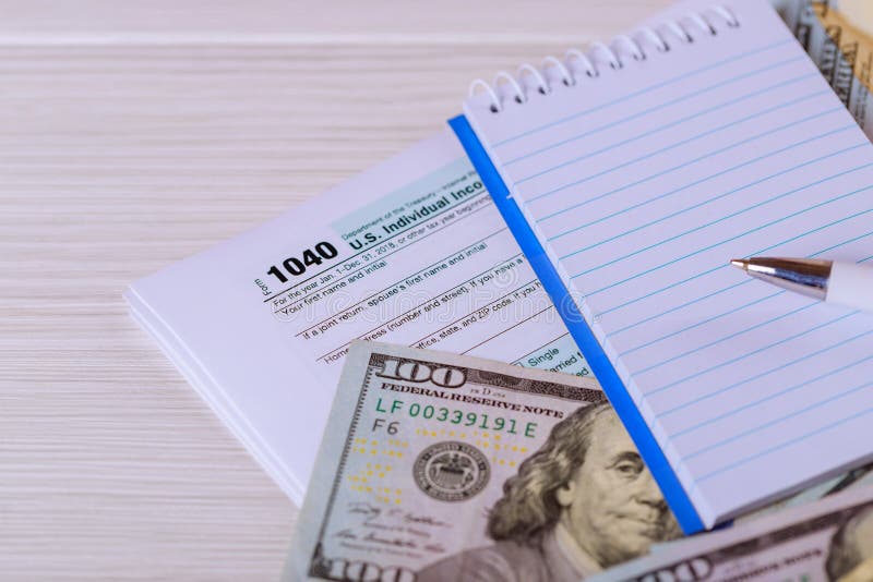 A pena, o caderno e as notas de dólar são mentiras no formulário de imposto U 1040 S Declaração de rendimentos individual da rend fotografia de stock royalty free A pena, o caderno e as notas de dólar são mentiras no formulário de imposto U 1040 S Declaração de rendimentos individual da rend fotografia de stock royalty free