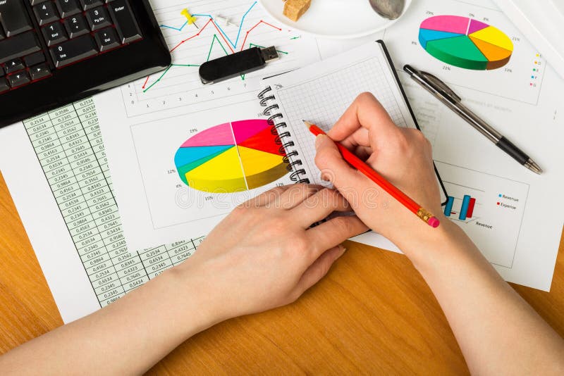 Pencil in female hand, notebook in background of your desktop. stock image
