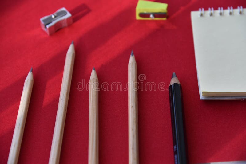 Pencils hole punch and notepad on a red background royalty free stock images