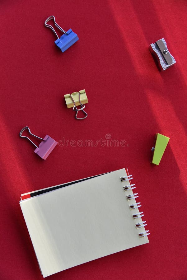 Pencils hole punch and notepad on a red background stock image