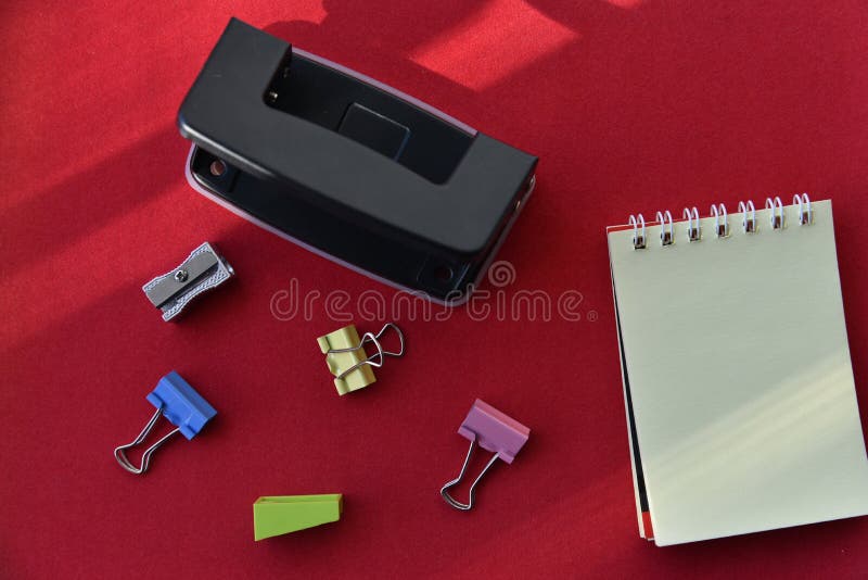 Pencils hole punch and notepad on a red background royalty free stock photos