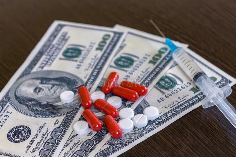 Pengar och piller med droger och en injektionsspruta på den medicinska tabellen arkivbild Pengar och piller med droger och en injektionsspruta på den medicinska tabellen arkivbild