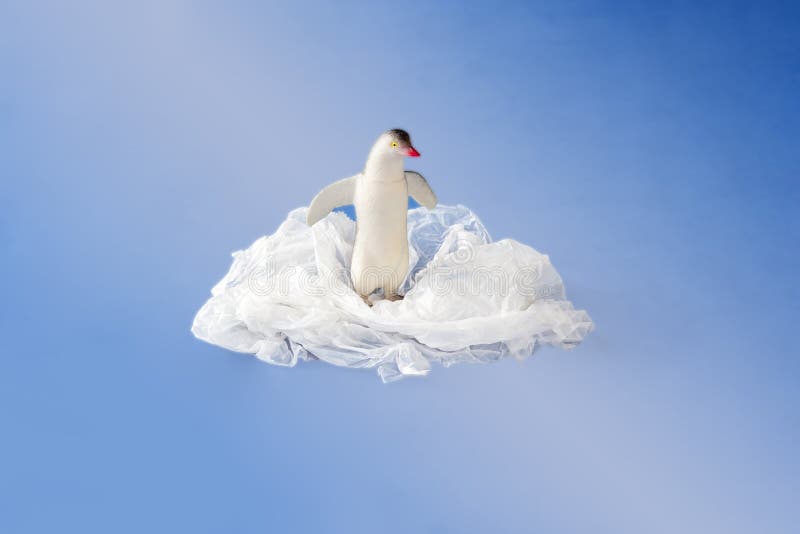 Penguin toy entangled in a plastic bag on blue background. Concept of plastic pollution. Environmental Problem. Copy space for stock photography