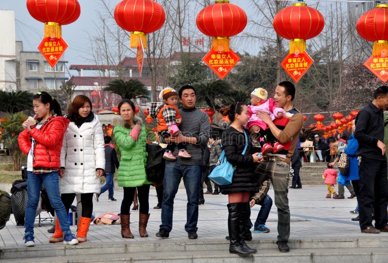 Families in Pengzhou City Park on a mild winter afternoon under a row of red Chinese New Year lanterns in Pengzhou, China. Families in Pengzhou City Park on a mild winter afternoon under a row of red Chinese New Year lanterns in Pengzhou, China.