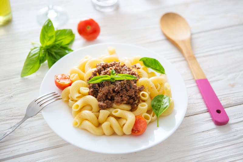 Penne italiano bolognese di cucina o pasto della pasta delle tagliatelle della salsa di Bolognaise su un piatto sulla tavola di l fotografia stock libera da diritti Penne italiano bolognese di cucina o pasto della pasta delle tagliatelle della salsa di Bolognaise su un piatto sulla tavola di l fotografia stock libera da diritti