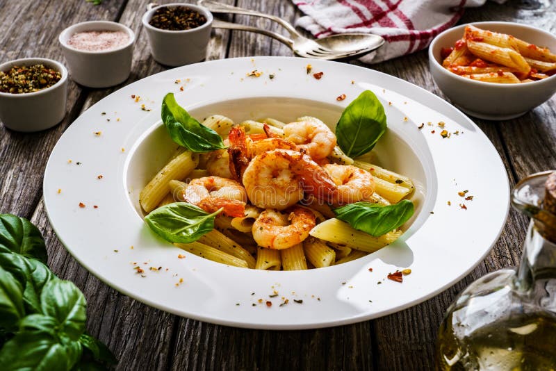 Penne mit gebratenen Garnelen auf Holztisch stockbilder