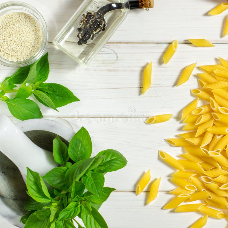 Penne Pasta, grüne Basilika, Parmesan, Sesam, Knoblauch, Chili, Eier liegen auf einem weißen Tisch stockfoto