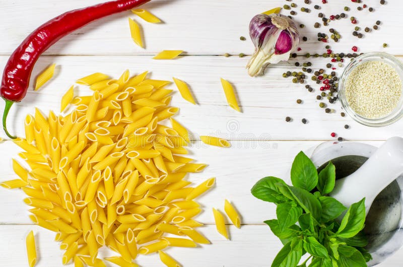 Penne Pasta, grüne Basilika, Parmesan, Sesam, Knoblauch, Chili, Eier liegen auf einem weißen Tisch stockbilder
