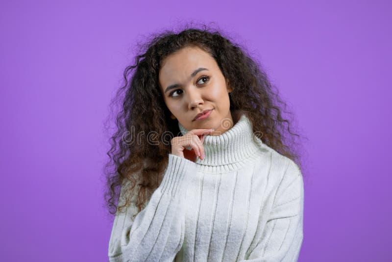 Pensatrice che guarda in violet studio. espressioni di facciata pensanti. bel modello in maglione con un'attraente fotografia stock