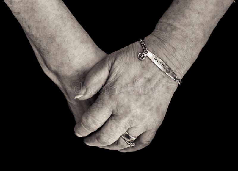 Pensioner`s hands with medical alert bracelet for diabetes. Mono