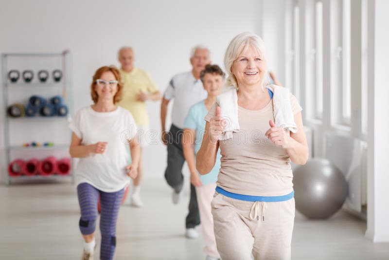 Happy active seniors exercising together in white spacious room. Happy active seniors exercising together in white spacious room