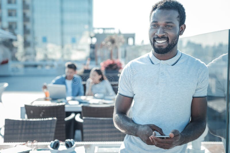 Pensive african american guy with smartphone dreaming and smiling royalty free stock images Pensive african american guy with smartphone dreaming and smiling royalty free stock images