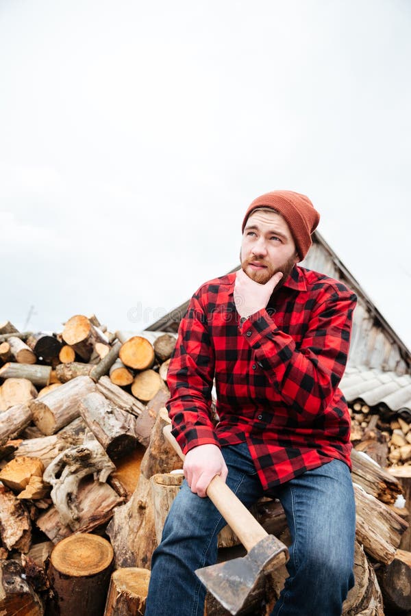 Pensive bearded man with axe sitting on logs and thinking royalty free stock images Pensive bearded man with axe sitting on logs and thinking royalty free stock images