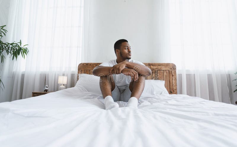 Pensive Black Guy Thinking Sitting In Bed In His Cozy Bedroom At Home, Havi...