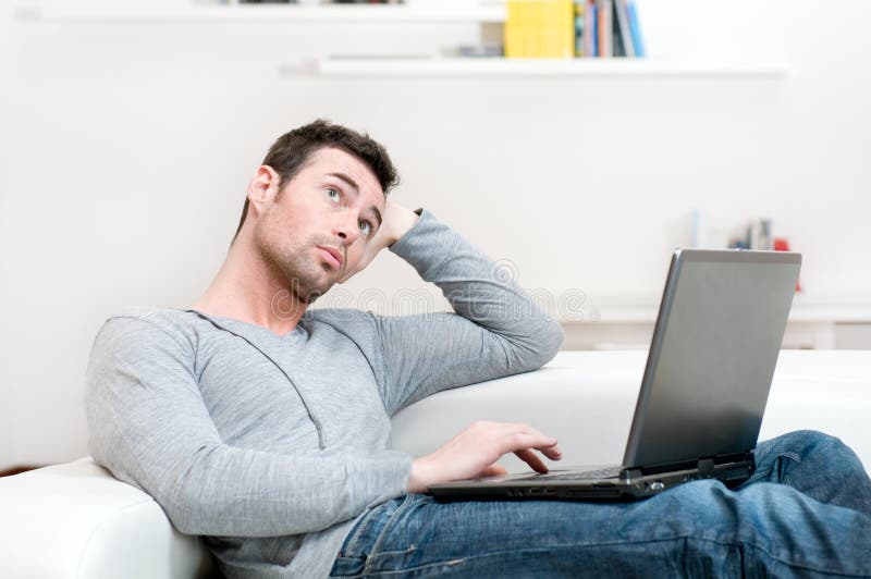 Pensive casual man working on laptop stock photography