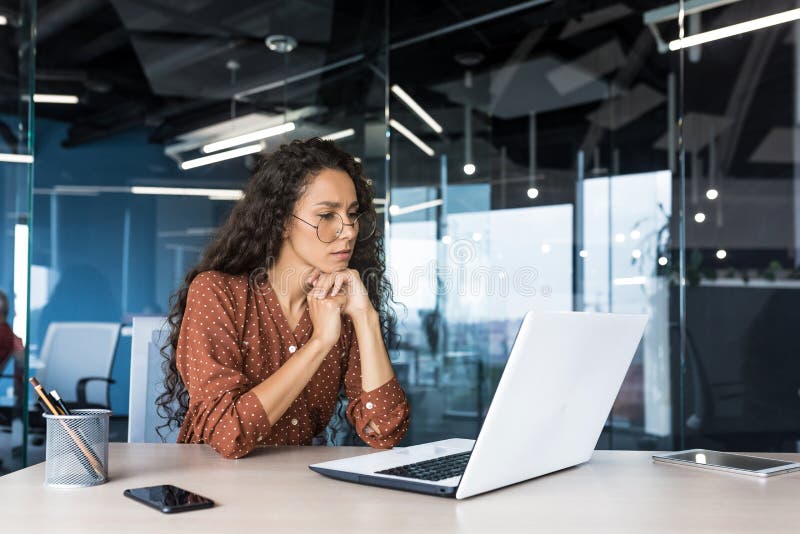 Pensive and focused female programmer web developer working in modern product development company Hispanic woman sitting royalty free stock photos
