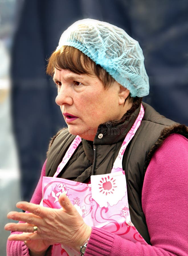 Photo of a very pensive looking dinner lady keeping a watchful eye on the diners under her care.