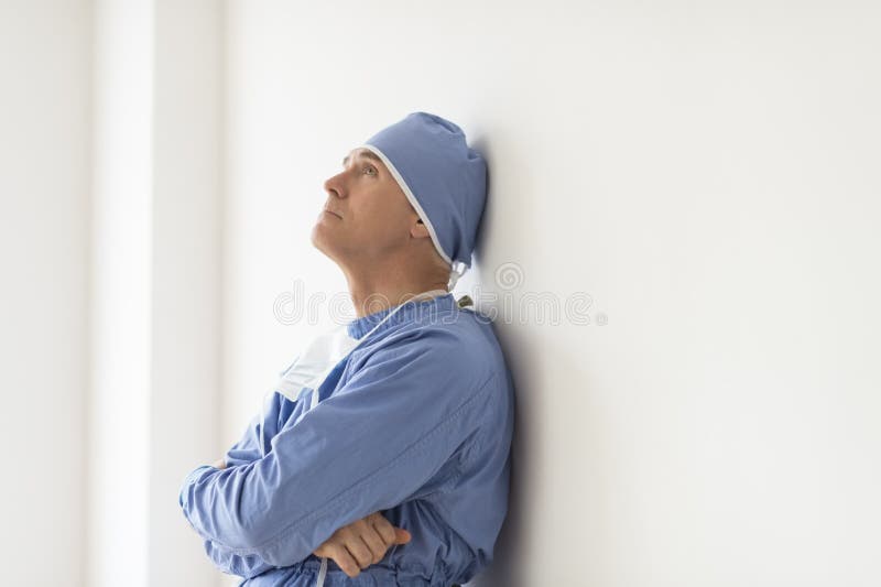 Pensive Surgeon With Arms Crossed Leaning On Wall