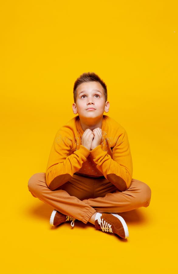 Pensive Teen Boy Sitting Cross-legged Stock Image - Image of yellow ...