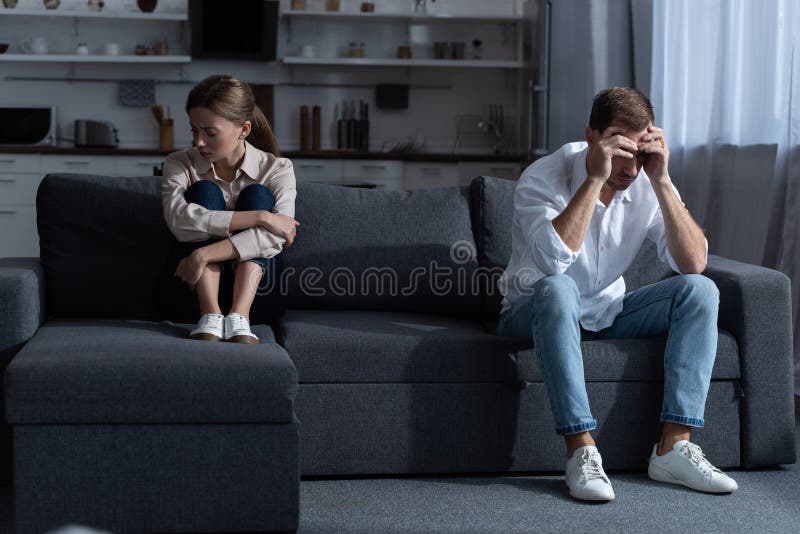 Pensive upset couple in living room at home