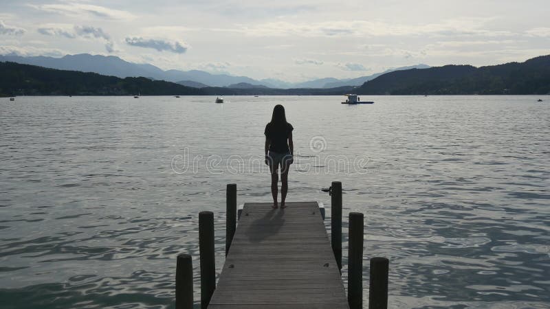 Woman with coffee cup standing on jetty over lake stock photo