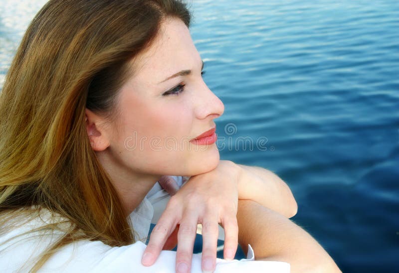 Closeup portrait einer schönen Frau mit einem nachdenklichen Ausdruck im Profil, mit Ausblick auf das Wasser.