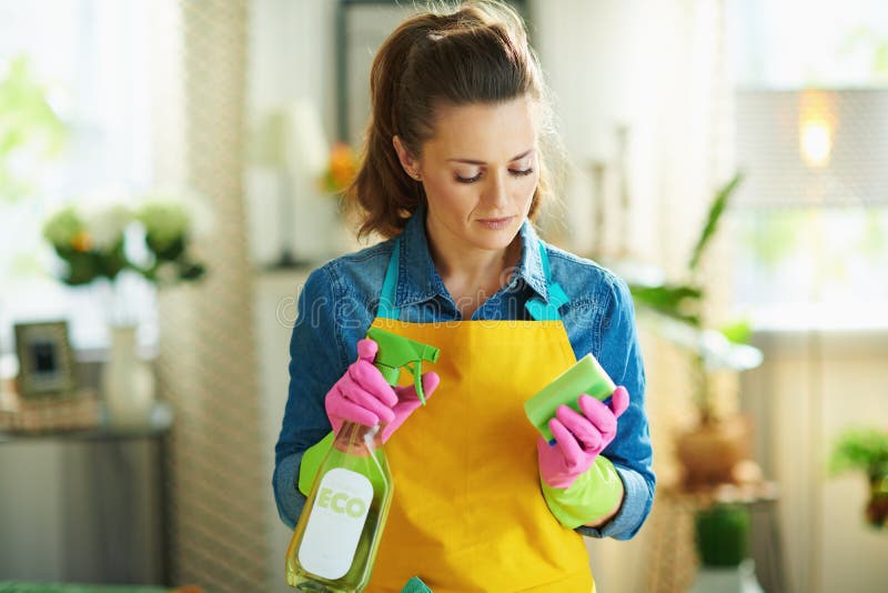 Pensive woman with cleaning agent and sponge housecleaning