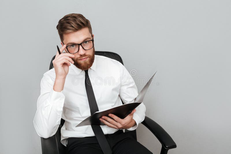 Pensive young businessman in eyeglasses holding a folder royalty free stock photo Pensive young businessman in eyeglasses holding a folder royalty free stock photo