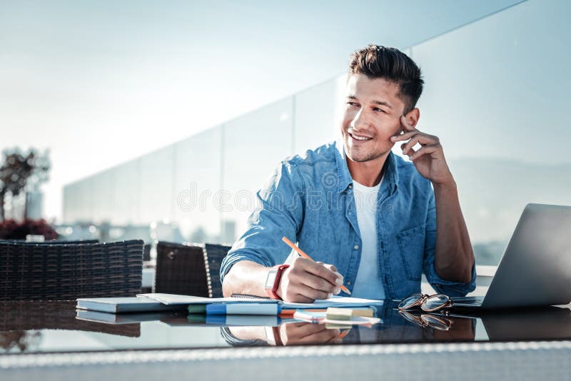 Pensive young gentleman smiling while working on laptop outdoors royalty free stock photos Pensive young gentleman smiling while working on laptop outdoors royalty free stock photos
