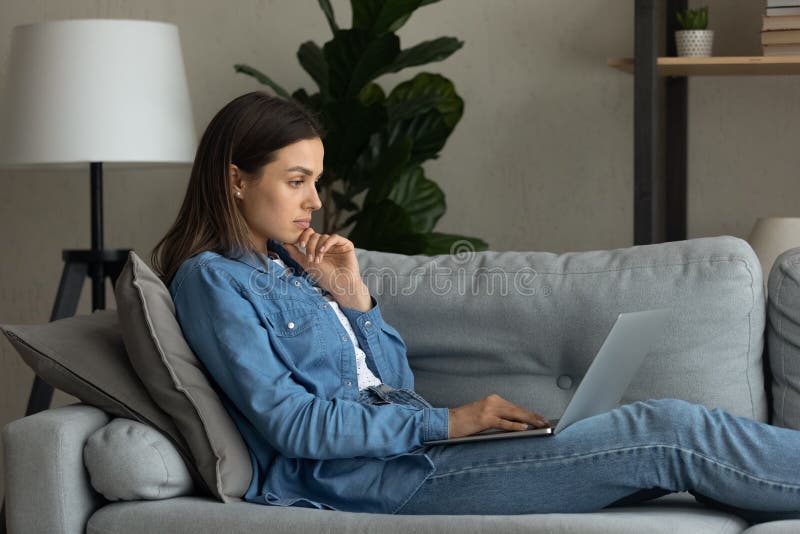 Pensive young female read post at blog on laptop screen