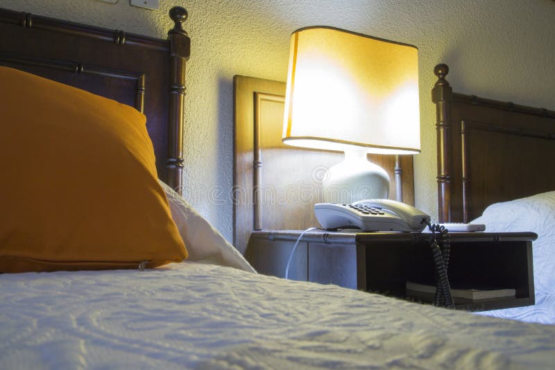 Pensão com camas, nightstand e lâmpada na noite foto de stock Pensão com camas, nightstand e lâmpada na noite foto de stock